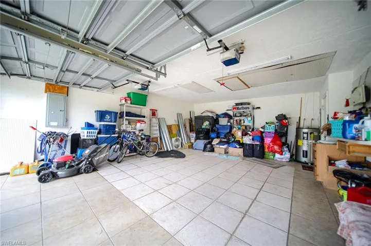 Garage featuring electric water heater, a garage door opener, and electric panel