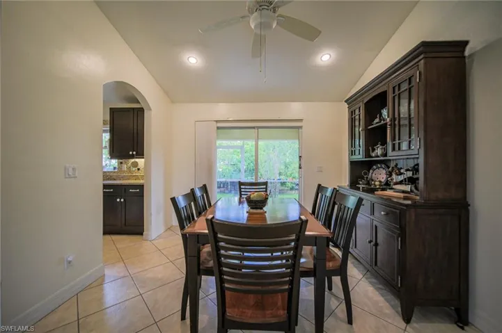 Dining area featuring vaulted ceiling, light tile patterned floors, ceiling fan, arched walkways, and recessed lighting