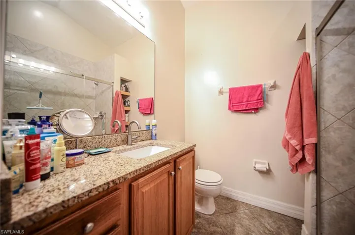 Bathroom featuring vanity, a tile shower, and tile patterned flooring