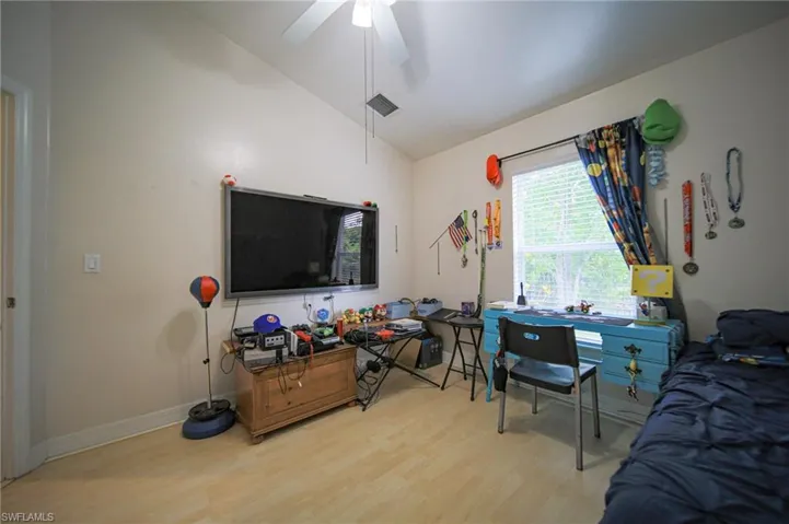 Bedroom with lofted ceiling, wood finished floors, and ceiling fan