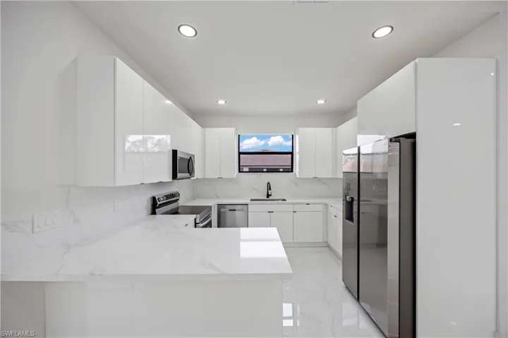 Kitchen featuring stainless steel appliances, a sink, recessed lighting, a peninsula, and backsplash
