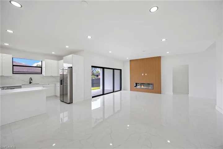 Unfurnished living room with light marble finish floors, a sink, recessed lighting, and a fireplace