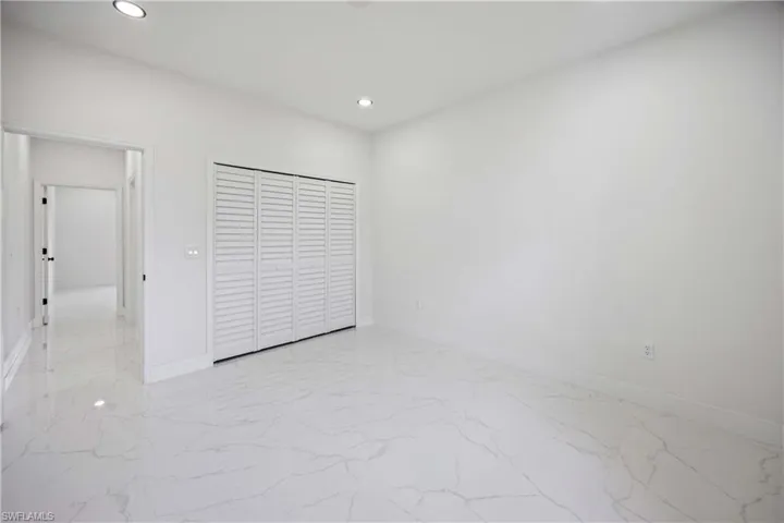 Unfurnished bedroom featuring light marble finish floors, recessed lighting, baseboards, and a closet