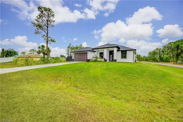 Prairie-style home featuring driveway, an attached garage, a front yard, and stucco siding
