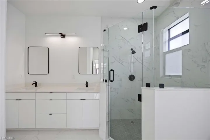 Full bathroom featuring marble look tile flooring, a marble finish shower, double vanity, and recessed lighting