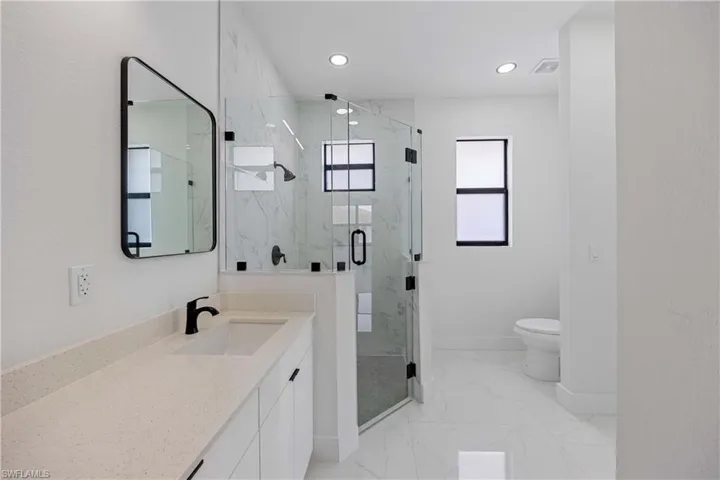 Full bath featuring baseboards, marble finish floors, recessed lighting, a marble finish shower, and toilet