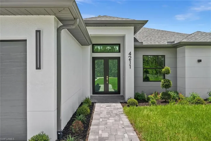 View of exterior entry with french doors, a shingled roof, and stucco siding