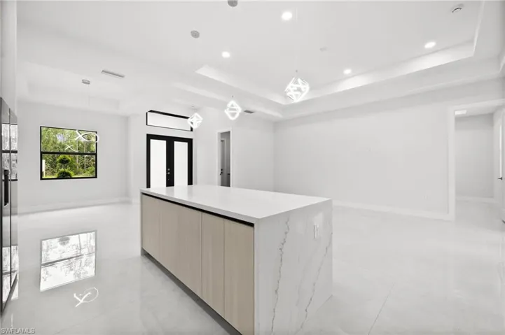 Kitchen featuring a tray ceiling, modern cabinets, french doors, open floor plan, and recessed lighting