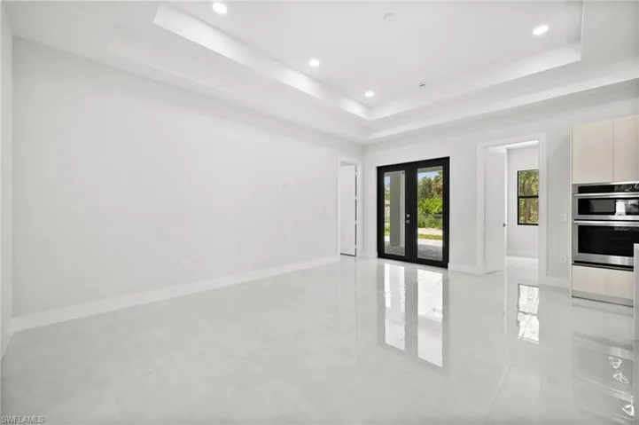 Empty room featuring a tray ceiling, recessed lighting, and light tile patterned flooring