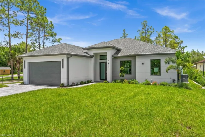 Prairie-style home featuring a garage, stucco siding, a front lawn, roof with shingles, and driveway