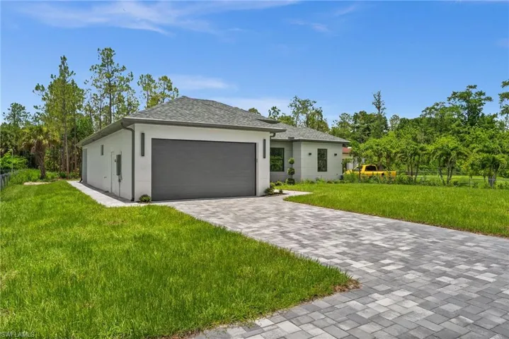 View of front of house with a garage, stucco siding, a front yard, and decorative driveway