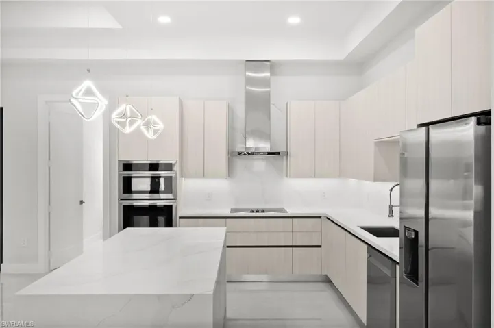Kitchen with stainless steel appliances, wall chimney exhaust hood, modern cabinets, light stone countertops, and recessed lighting