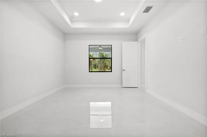 Empty room featuring a raised ceiling, recessed lighting, a ceiling fan, and light tile patterned floors