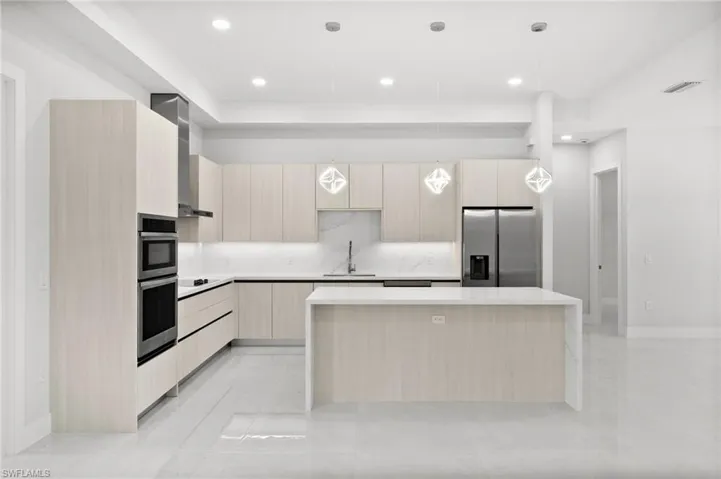 Kitchen featuring stainless steel appliances, modern cabinets, light brown cabinets, a kitchen island, and recessed lighting