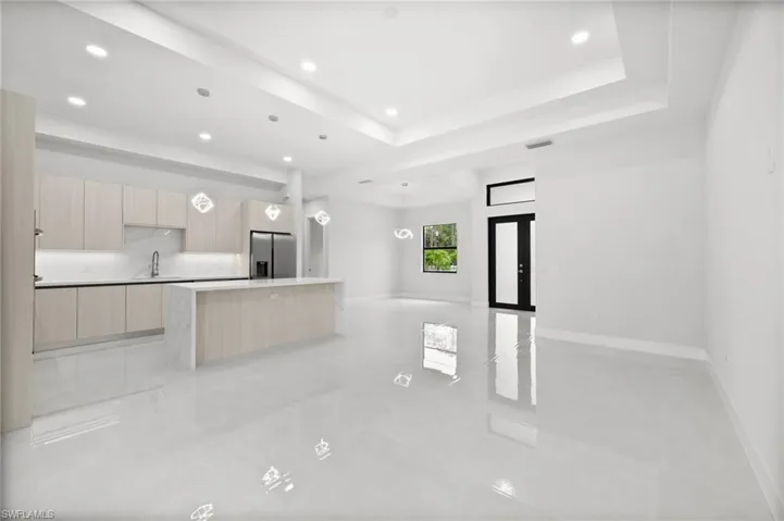 Unfurnished living room with recessed lighting, light tile patterned floors, and a tray ceiling