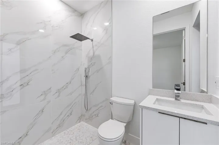 Bathroom with vanity, tiled shower, and toilet