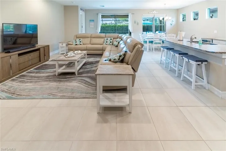 Living room featuring a notable chandelier, sink, and light tile floors