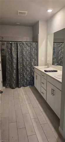 Bathroom featuring a double vanity with white cabinetry, light-colored countertops, and dual undermount sinks