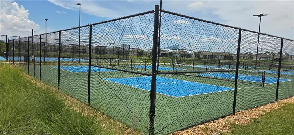 Multiple hard-surface courts featuring blue and green playing areas, enclosed by black chain-link fencing