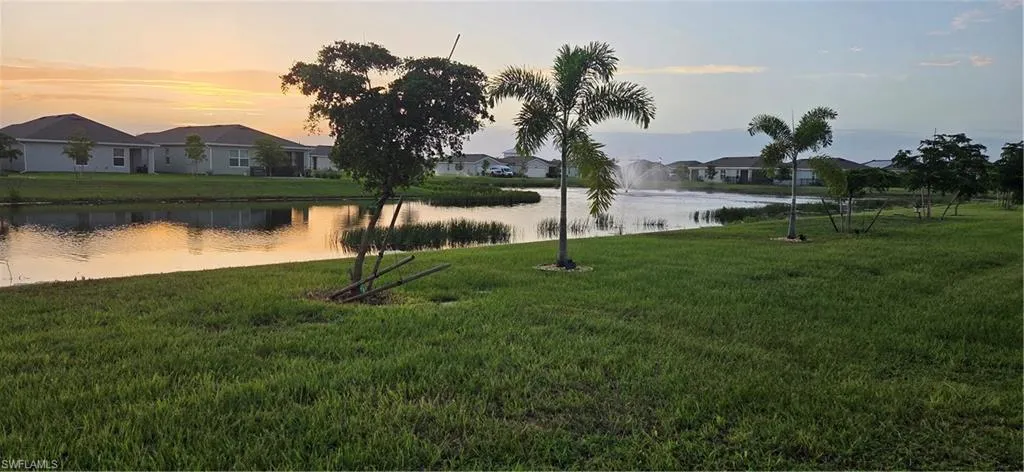 Expansive green lawn bordering a tranquil pond with a fountain feature