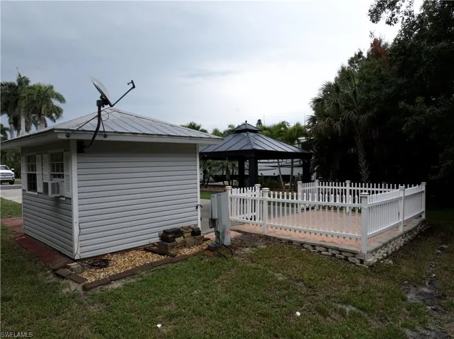Rear view of accessory building featuring a gazebo, cooling unit, and an outbuilding