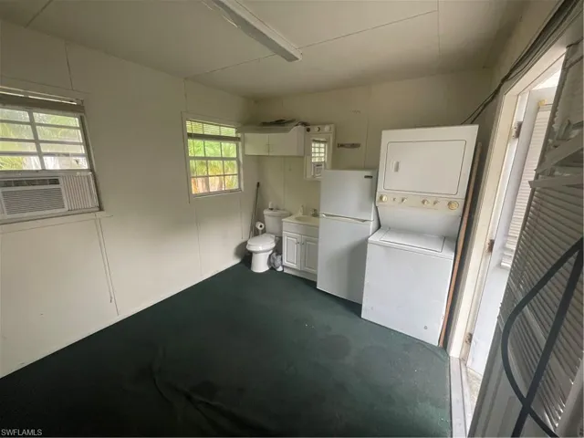 Laundry room with stacked washer / drying machine, a sink, and cooling unit