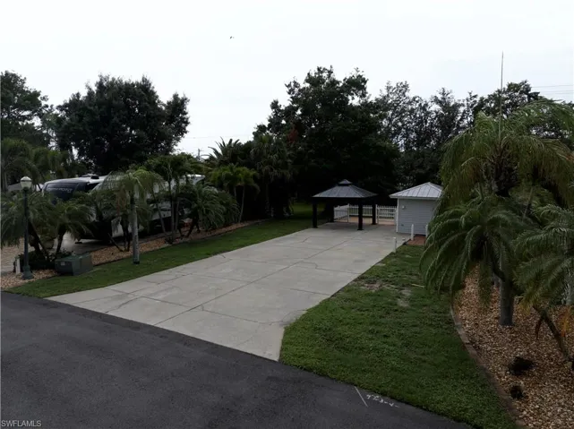 View of grassy yard with driveway and a gazebo