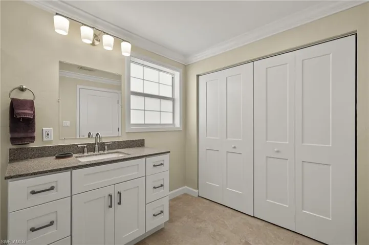 Bathroom with crown molding, vanity, and baseboards