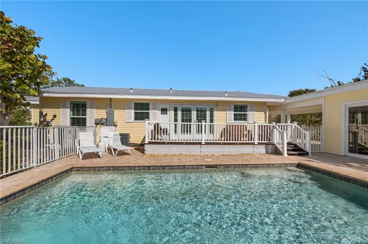 Back of house with a wooden deck, a fenced in pool, and fence