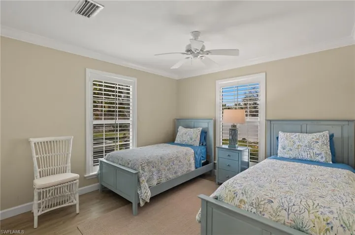 Bedroom with light wood finished floors, visible vents, and crown molding