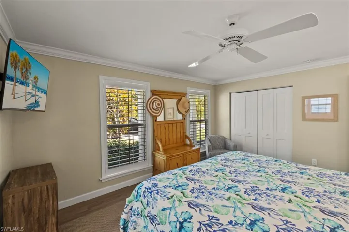 Bedroom with baseboards, a ceiling fan, dark wood-style floors, ornamental molding, and a closet