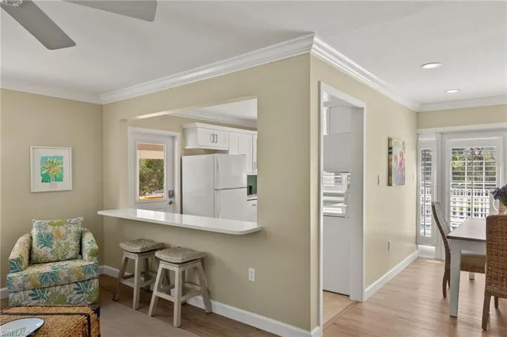 Kitchen with light wood finished floors, white cabinetry, freestanding refrigerator, and a kitchen breakfast bar
