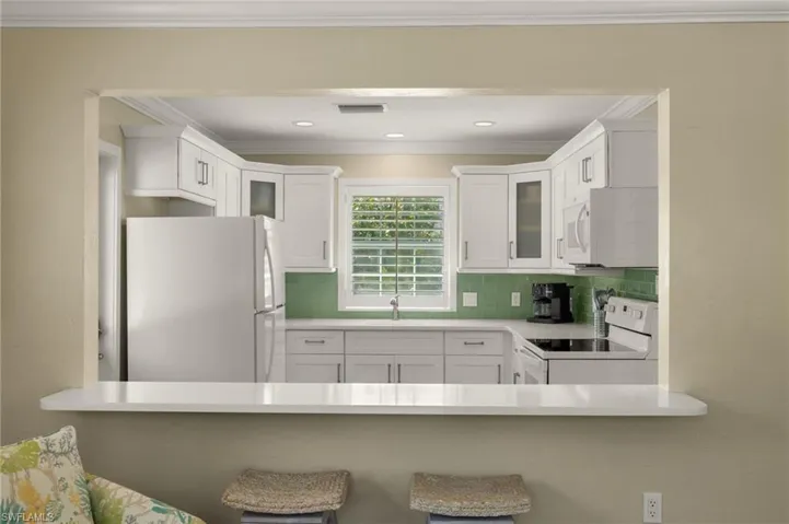 Kitchen with white appliances, tasteful backsplash, visible vents, glass insert cabinets, and a sink
