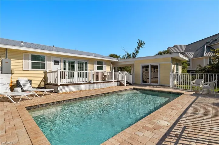 Rear view of house featuring a fenced in pool, a patio, metal roof, fence, and a wooden deck