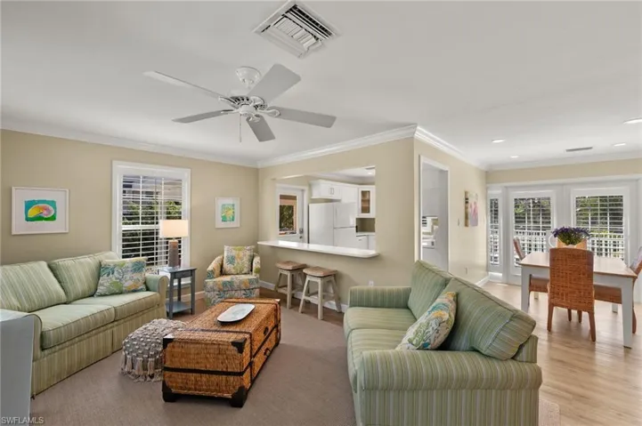 Living room featuring baseboards, light wood-style flooring, visible vents, and crown molding