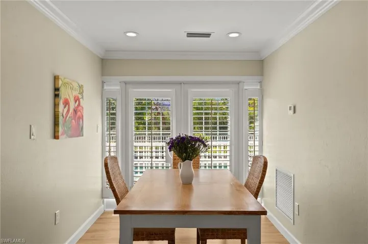 Dining room featuring baseboards, light wood finished floors, visible vents, and crown molding