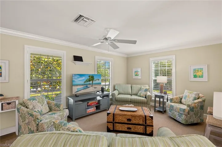 Living room with ornamental molding, a healthy amount of sunlight, and visible vents