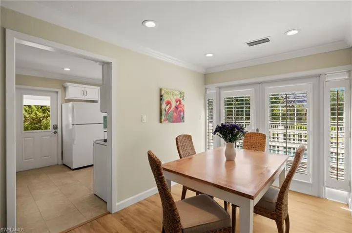 Dining area with light wood-style floors, visible vents, and crown molding
