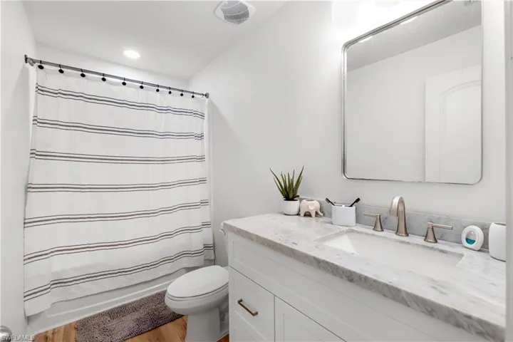 Bathroom featuring vanity, light wood-style flooring, shower / tub combo with curtain, and recessed lighting