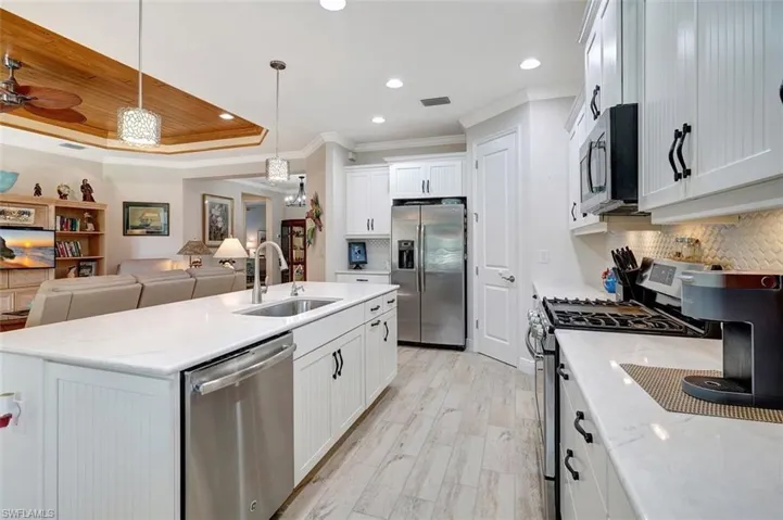 The kitchen has all the necessary appliances to make life easier with a gas stove & mounted microwave.  The cabinets are wainscoted with undermounted lighting & planked flooring.