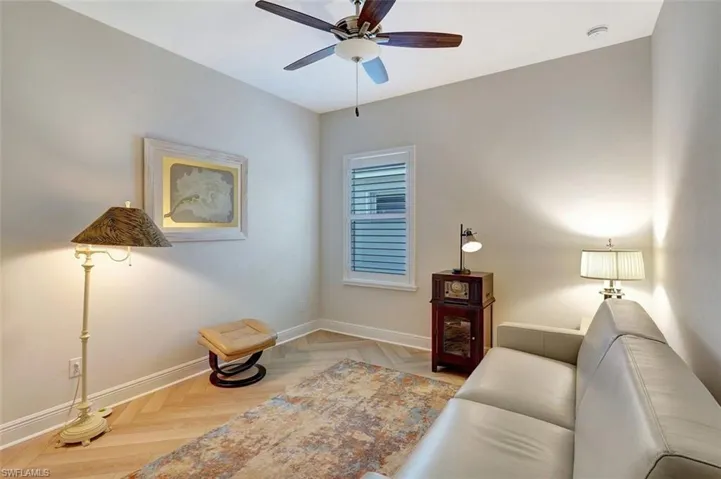 This is the large third bedroom with planked flooring, carpet covering & large sofa.