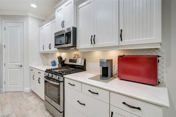 The back splash, wainscoted cabinets & stainless appliances are part of the kitchen.  The door leads to the enclosed pantry.