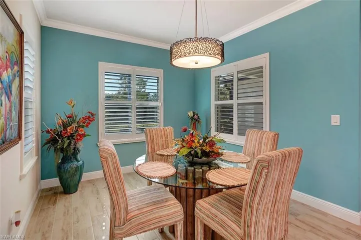 Large dining area with dual walled color and planked flooring, dining lighting & glass table.