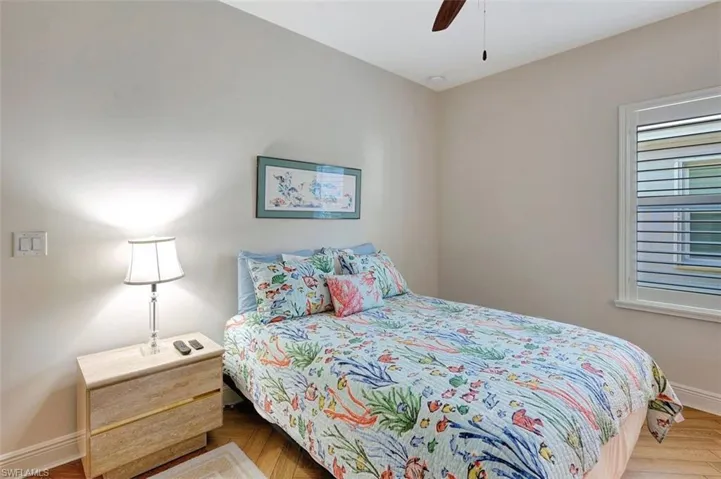 Plenty of room with planked flooring, side bureau & lamp.