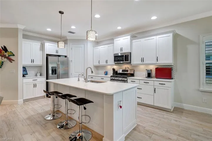 The kitchen is updated with quartz countertops, planked flooring, stainless appliances, undermounted lighting, and recessed lighting with pendants.