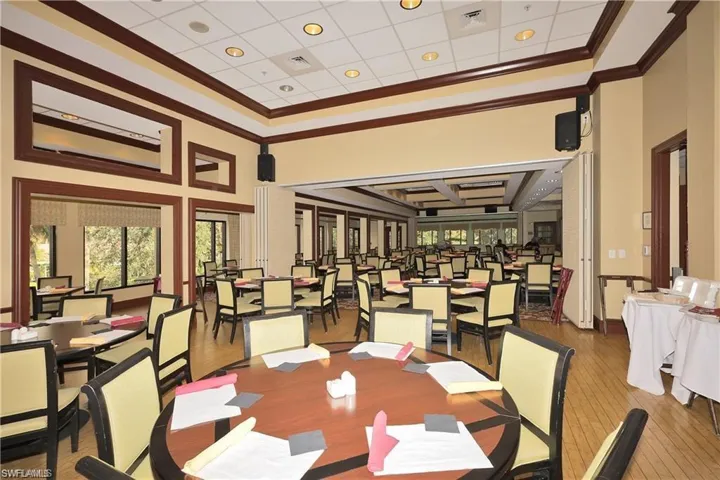 Dining area with wood-type flooring, a towering ceiling, and ornamental molding