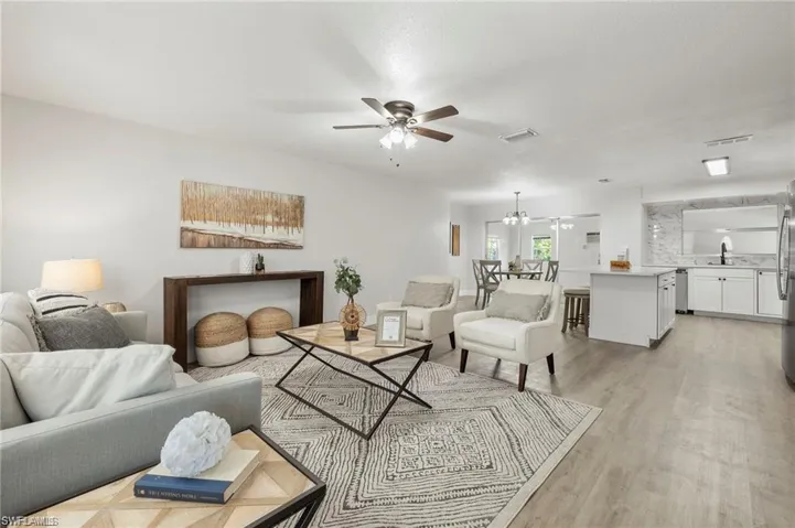 Living room featuring a ceiling fan, light wood-style flooring, and a chandelier