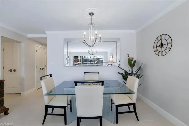 Tiled dining room featuring an elegant chandelier and crown molding.