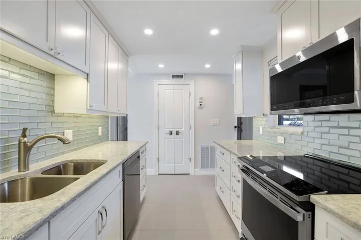 Kitchen featuring quartz counters, decorative backsplash, white cabinets, new stainless steel appliances.