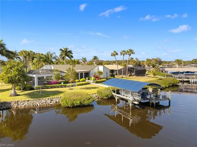 Dock area featuring a lawn, a water view, and glass enclosure